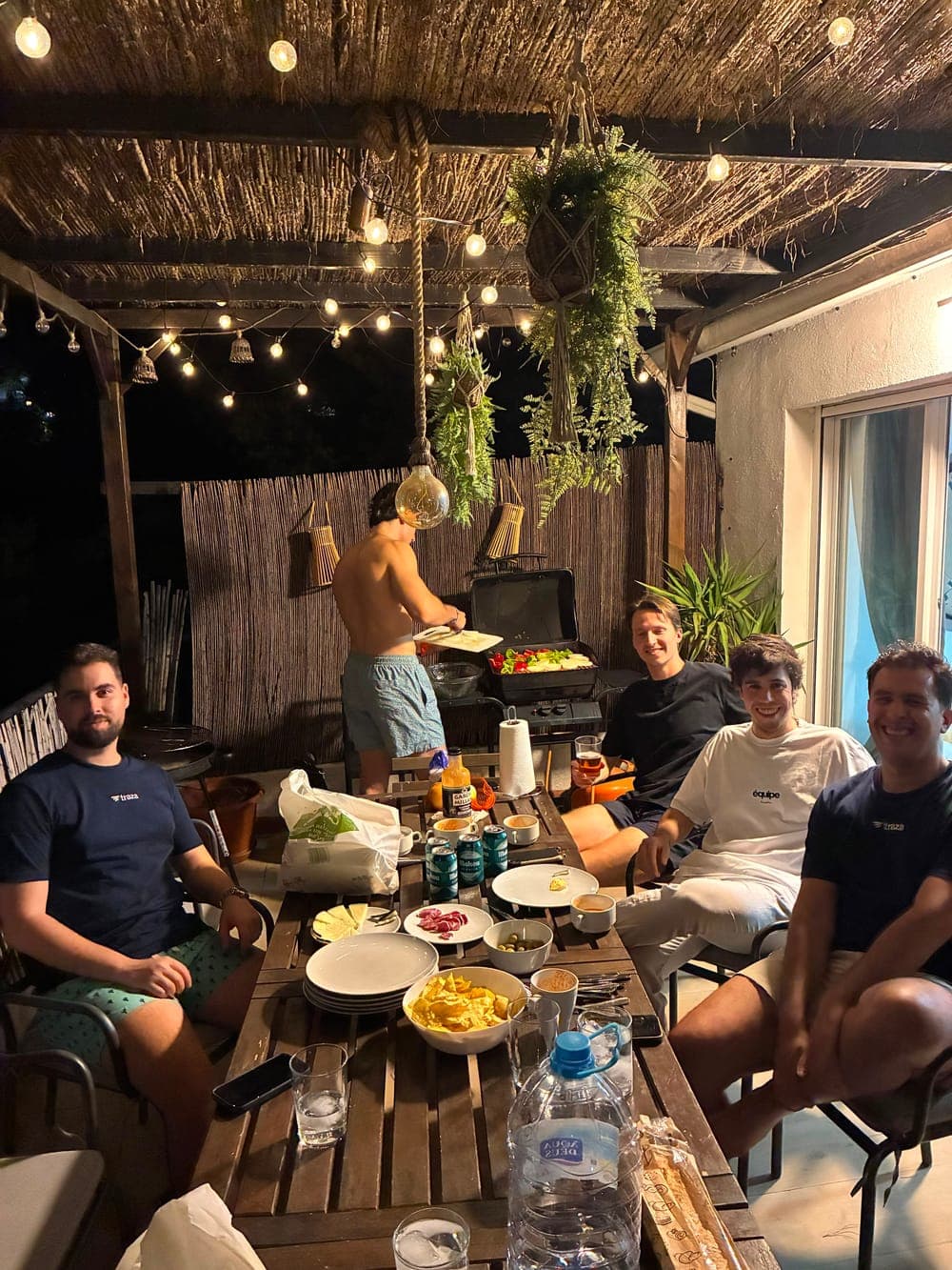 The Traza team at a barbecue dinner on a terrace at night.